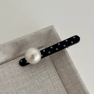 Detailed close-up of a sweet black and white polka dot hair clip with a large faux pearl.