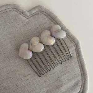 Detailed view of sweet iridescent heart hair comb with metal prongs for chic hairstyles.