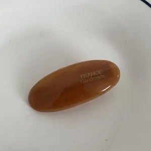 Primo piano di un'elegante molletta per capelli ovale in acetato marrone con texture e lavorazione.