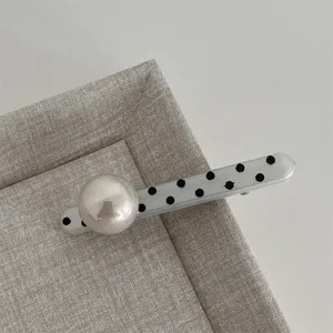 Close-up detail of the cute black and white polka dot hair clip with large pearl decoration.