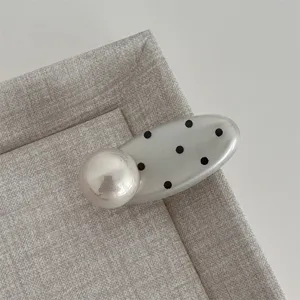 Close up detail view of the sweet style polka dot hair clip featuring a large pearl accent.