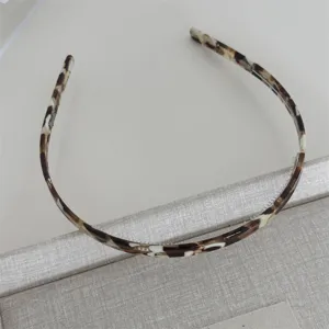 Tortoiseshell thin hair hoop with teeth, glossy acetate finish, close-up detail view.