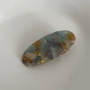 Vista dettagliata della molletta per capelli ovale in acetato multicolore con motivo marmorizzato.