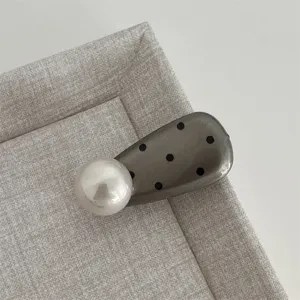 Close-up detail of the sweet polka dot pearl hair clip, showing the glossy finish and elegant design.