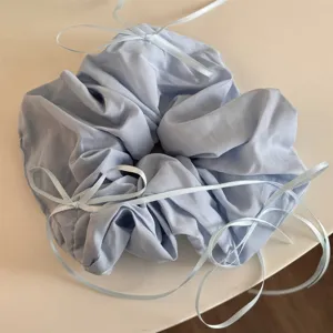 Vue détaillée d'un chouchou en tissu bleu clair avec des rubans élégants pour coiffures.