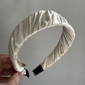 Close-up of elegant pleated satin headband in cream white, featuring chic textured design.
