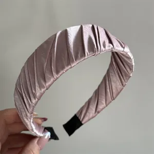 Close-up detail of a minimalist pleated satin hairband in mauve, elegant hair accessory.