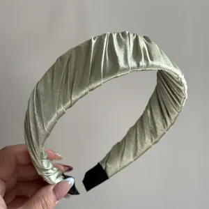 Detail shot of the light green pleated satin headband, showing delicate wrapped fabric texture.