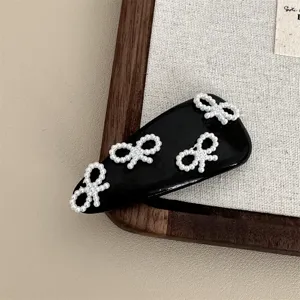 Exquisite black leather hair clip featuring elegant white pearl bows for a chic ballet style.