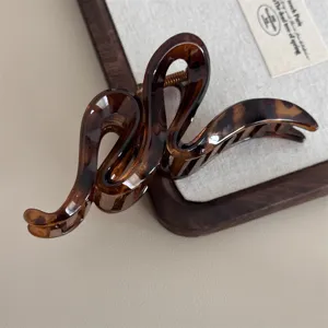 Élégante pince à cheveux vague écaille de tortue marron pour femmes, accessoire de coiffure minimaliste.