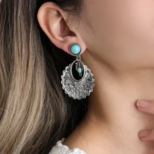 Retro silver turquoise carved drop earrings detail, bohemian ethnic style jewelry close up.