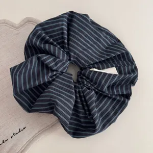 Detail view of the black and blue striped fabric scrunchie, showcasing textured retro hair tie.