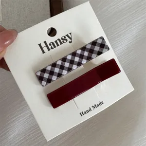 Mooi detail van geruite en rode haarspelden op kaart, stijlvolle haaraccessoire voor dames.