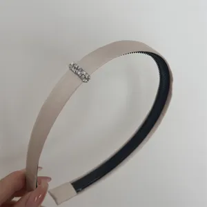 Detailed view of the elegant beige satin headband with sparkling crystal rhinestone decoration.