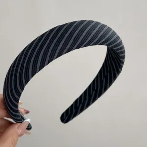 Detailed view of a chic black and gray striped wide fabric headband, elegant hair accessory.