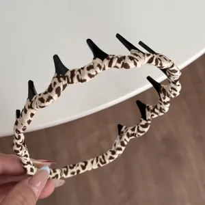 Detailansicht des Leopardenmuster-Haarreifs mit schwarzem Zahnkamm und weichem Stoffmaterial.