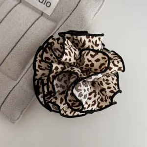 Nahaufnahme im Detail von dem stylischen Stoff Leopardenmuster Haargummi mit schwarzem Rand.