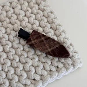 Detail de pince a cheveux en tissu carre marron, gros plan accessoire epingle cote.