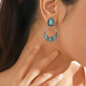 Close-up detail shot of vintage ethnic style turquoise crescent drop earrings on model ear.
