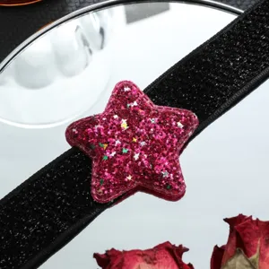Primo piano dettagliato di una collana girocollo con stella rosa glitterata su banda nera.