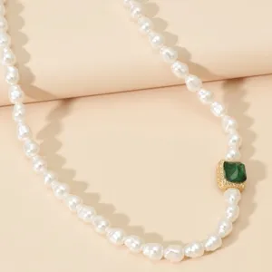 Primo piano dettagliato della collana di perle con elegante ciondolo quadrato verde.