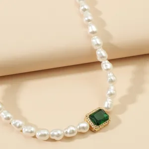 Dettaglio in primo piano della raffinata collana di perle con ciondolo verde chiaro.