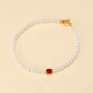 Elegante collana girocollo di perle vintage con gemma rossa brillante e chiusura dorata.