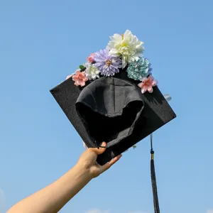 Close-up detail of graduation cap decorated with colorful artificial flowers and black tassel.