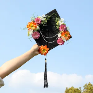 Detailed view of a graduation cap decorated with colorful floral wreaths and pearls.