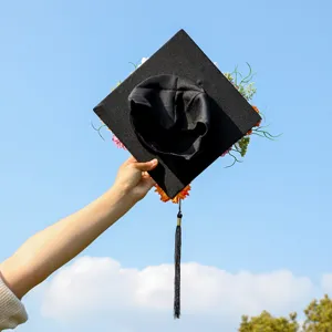 Close-up detail of graduation cap decorated with colorful floral arrangement and black tassel.