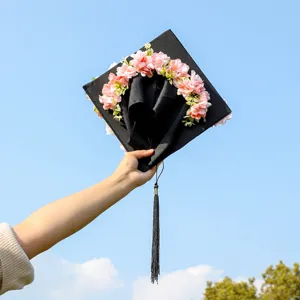 Graduation cap with pink floral decor, black square cap with tassel for graduation photo party.