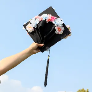 Graduation cap with colorful artificial flowers, black mortarboard with tassel for party.