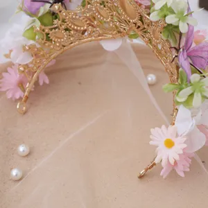 Close-up detail of golden filigree tiara with artificial silk flowers, pearls and sheer veil.