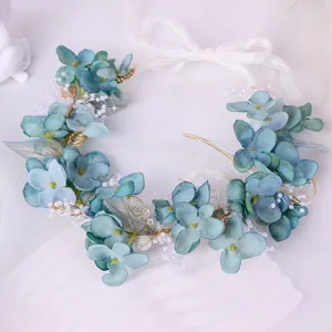 Detailed view of the blue floral hair wreath, featuring silk flowers, pearls, and mesh leaves.