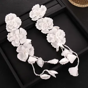 White floral bridal hair accessory detail, elegant handmade pearl tassel wedding headpiece.