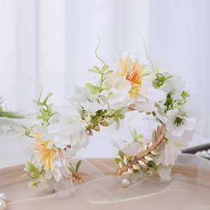 Closeup of baroque floral crown headpiece with white silk flowers and gold leaf accents.