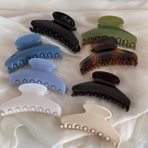 Detail shot of stylish acrylic hair claws in multiple colors on white fabric background.