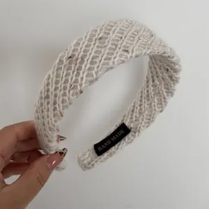 Beige wide knitted woolen headband detail, soft textured winter hair accessory for women.