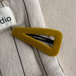 Mustard yellow velvet triangle hair clip detail shot, elegant vintage side clip texture.