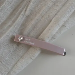 Épingle à cheveux rose élégante avec cœur en strass étincelant et impression de lettres minimaliste.