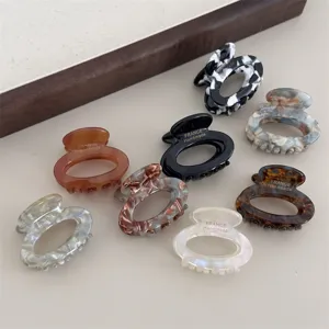 Closeup of small oval acetate hair claws in various colors and patterns, detailed design.