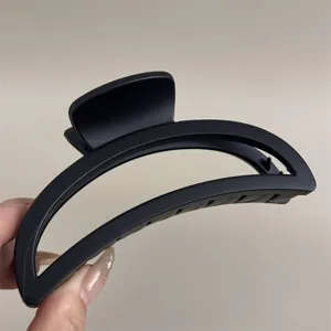 Gros plan pince a cheveux noire mate, pince crabe demi-cercle elegante pour coiffure quotidienne.