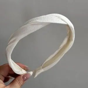 Detailopname van witte gedraaide satijnen haarband, elegante haarring voor dagelijks gebruik.