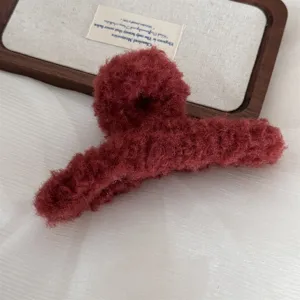 Detailed shot of dark red plush hair claw clip, soft fluffy winter hair accessory.