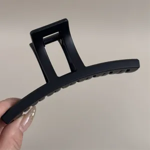 Détail de grande pince à cheveux noire mate, élégant clip requin pour coiffure chic.