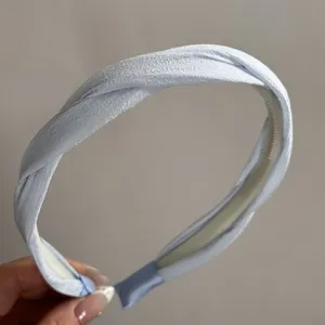 Gedetailleerd overzicht van de elegante lichtblauwe satijnen gedraaide haarband met textuur.
