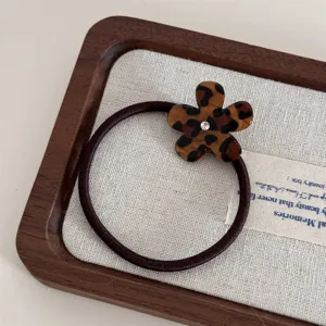 Leopard print acetate flower hair tie detail with sparkling center rhinestone on fabric tray.