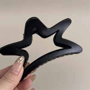Détail de la pince à cheveux étoile noire mate, accessoire élégant et tendance au quotidien.