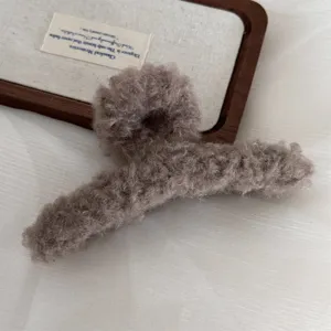 Detailed shot of large brown plush hair claw clip for women, fluffy winter hair accessory.