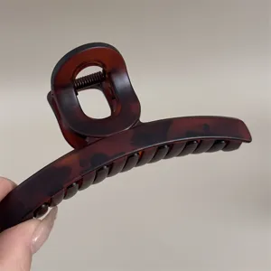 Vue rapprochée détaillée d'une grande pince à cheveux marron avec ressort métallique.